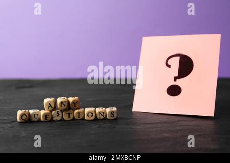 Formulieren Sie Fragen aus Holzwürfeln, und notieren Sie sie mit einem Satzzeichen auf dem Tisch aus schwarzem Stein Stockfoto