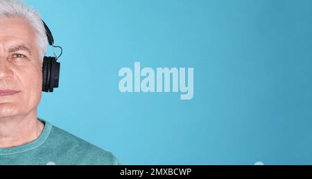 Ein erwachsener Mann hört Musik mit Kopfhörern auf blauem Hintergrund, Platz für Text. Bannerdesign Stockfoto