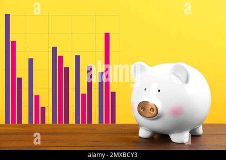 Weißes Sparschwein und Grafik auf gelbem Hintergrund Stockfoto