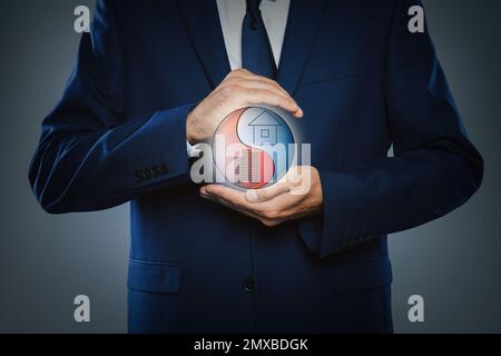 Geschäftsmann, der ein Gleichgewicht zwischen Leben und Arbeit zeigt, auf dunklem Hintergrund, Nahaufnahme Stockfoto