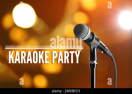 Modernes Mikrofon und Text-KARAOKE-PARTY auf verschwommenem Hintergrund Stockfoto