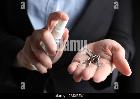 Geschäftsfrau, die Antiseptikum auf Schlüssel spritzt, Nahaufnahme Stockfoto