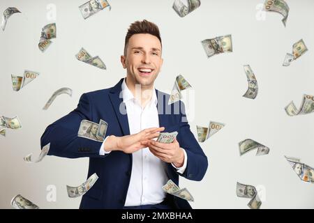 Ein Mann, der amerikanische Dollar auf hellgrauem Hintergrund wirft Stockfoto