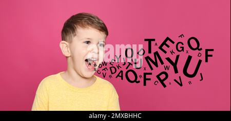 Porträt eines kleinen Jungen mit Buchstaben auf pinkfarbenem Hintergrund. Sprachtherapiekonzept Stockfoto