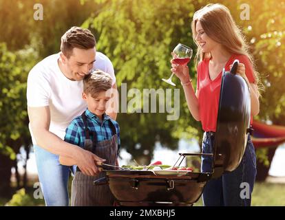 Glückliche Familie mit Grill mit modernen Grill im Freien Stockfoto