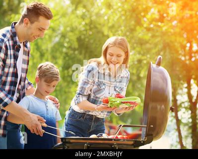 Glückliche Familie mit Barbecue mit modernem Grill im Freien an sonnigen Tagen Stockfoto