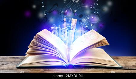 Symphonie mit musikalischen Noten aus einem offenen Buch auf einem Holztisch Stockfoto