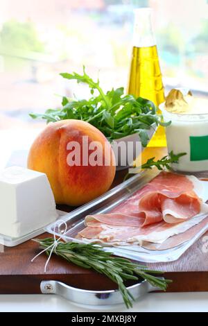 Zutaten für die Zubereitung der Mahlzeiten Joghurt, Ziegenkäse, Olivenöl, Schinken, Rosmarin, Pfirsich Stockfoto
