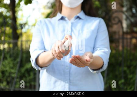 Frau, die im Freien Antiseptikum auf die Hand spritzt, Nahaufnahme. Virenschutz Stockfoto