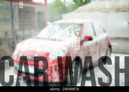 Text Autowäsche und Automobil bedeckt mit Schaum auf dem Hintergrund Stockfoto