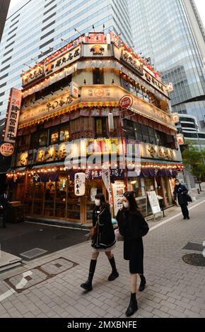 Ein altes japanisches Gebäude (Fischrestaurant) mit modernen Wolkenkratzern rundherum in Hibiya, Tokio, Japan. Stockfoto