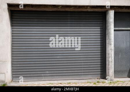 Metallischer grauer Vorhang an der Fassade, geschlossener, rollengrauer Garagentorzugang Stockfoto