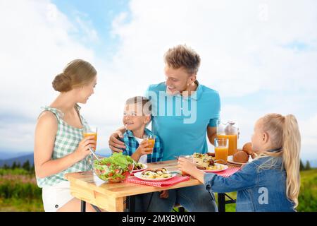 Glückliche Familie mit Picknick am Tisch im Park Stockfoto