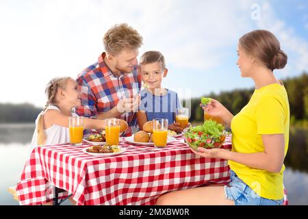 Glückliche Familie mit Picknick am Tisch im Park Stockfoto