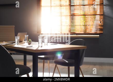 Stilvolle Büroeinrichtung mit Holztisch am Morgen Stockfoto