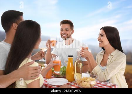 Eine Gruppe von Freunden, die ein Picknick am Tisch im Park machen Stockfoto