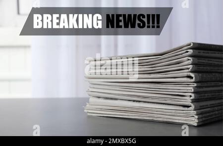 Zeitungsstapel mit Phrase Breaking News auf grauem Tisch. Journalistenarbeit Stockfoto