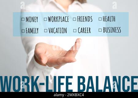 Konzept der Work-Life-Balance. Eine Frau, die eine Liste von Wörtern auf hellem Hintergrund vorführt, Nahaufnahme Stockfoto