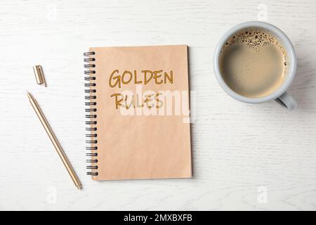 Notizbuch mit GOLDENEN REGELN und Tasse Kaffee auf Holzhintergrund, Draufsicht Stockfoto