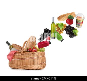 Verschiedene Produkte fallen in einen Picknickkorb auf weißem Hintergrund Stockfoto