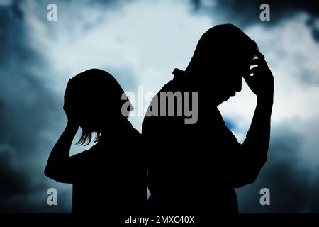 Silhouetten eines streitenden Paares gegen den Himmel mit schweren Regenwolken. Beziehungsprobleme Stockfoto