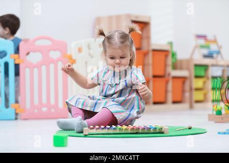 Süßes kleines Kind, das mit Xylophon auf dem Boden spielt Stockfoto