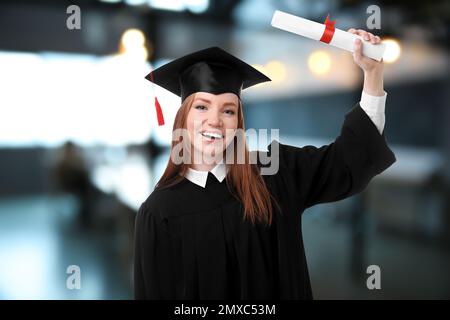 Glückliche Schülerin mit Abschlussmütze und Diplom im Amt Stockfoto