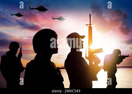 Silhouetten von Soldaten in Uniform mit Sturmgewehren und Militärhubschraubern, die draußen patrouillieren Stockfoto