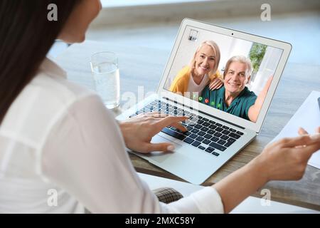 Junge Frau, die zu Hause mit ihren Großeltern per Video chatte, konzentriert sich auf den Bildschirm Stockfoto