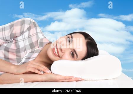 Junge Frau, die im Bett liegt. Blauer Himmel im Hintergrund Stockfoto