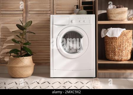 Moderne Waschmaschine und Regal im Waschraum Innenraum Stockfoto