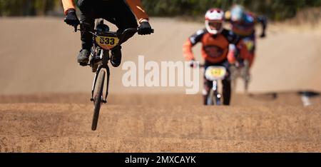 BMX-Fahrer, die in der Kinderklasse auf der Geländestrecke gegeneinander antreten Stockfoto