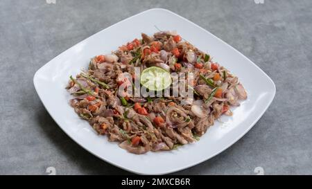 Huhn oder Rindfleisch mit traditionellem indonesischen Sambal. Zwiebeln, Chilis, Kokosöl, Limettenblätter, Salz. Serviert auf einem weißen Teller und einem Steinsockel. Stockfoto