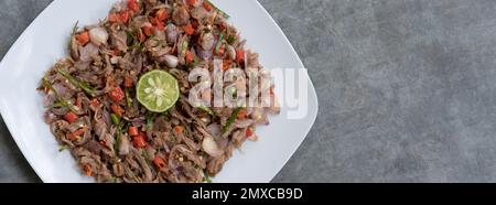 Huhn oder Rindfleisch mit traditionellem indonesischen Sambal. Zwiebeln, Chilis, Kokosöl, Limettenblätter, Salz. Serviert auf einem weißen Teller und einem Steinsockel. Stockfoto