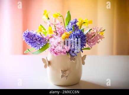 Frische, wunderschöne Frühlingsblumen in Vase auf dem Tisch. Osterdekoration für Zuhause. Stockfoto