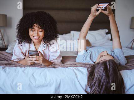 Videoanrufe, Telefon und Freunde mit Frauen während der Übernachtung für Kommunikation, Internet und Kontakt. Glücklich, entspannt und lächelt mit dem Mädchen, das im Schlafzimmer liegt Stockfoto