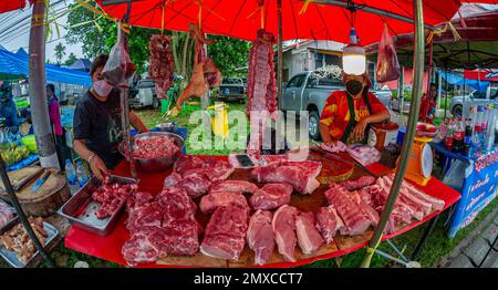 24. Januar 2023 - Chumphon Thailand - überfüllter Markt mit Schweinefleisch. Ein Verkäufer mit einer Maske hinter dem Stand. Stockfoto