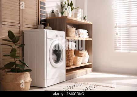 Moderne Waschmaschine und Regal im Waschraum Innenraum Stockfoto
