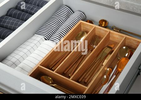 Die Schublade mit verschiedenen Utensilien und gefalteten Handtüchern öffnen. Ordnung in der Küche Stockfoto