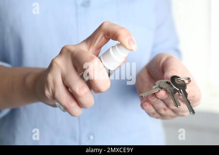 Frau, die Antiseptikum auf Schlüssel spritzt, Nahaufnahme Stockfoto