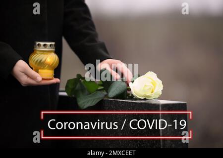 Beerdigungszeremonie für Coronavirus-Opfer. Frau mit Kerze und Rose in der Nähe des Grabsteins draußen, Nahaufnahme. Stockfoto