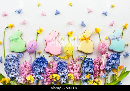 Osterkonzept mit lila und rosa Hyazinthen, Ostereiern und Keksen auf weißem Hintergrund. Flach liegend, Draufsicht. Stockfoto