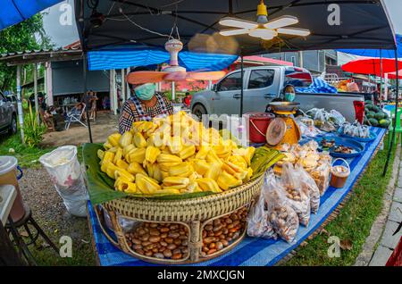 24. Januar 2023 - Chumphon Thailand - überfüllter Markt, auf dem Obst verkauft wird. Verkäufer mit einer Maske hinter dem Stand. Stockfoto