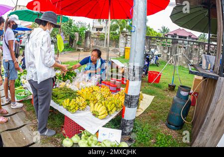 24. Januar 2023 - Chumphon Thailand - überfüllter Markt, der Bananen verkauft. Verkäufer mit einer Maske hinter dem Stand. Stockfoto