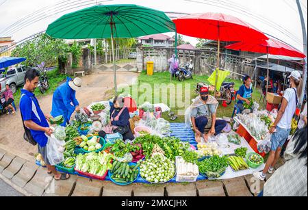 24. Januar 2023 - Chumphon Thailand - überfüllter Gemüsemarkt. Verkäufer mit einer Maske hinter dem Stand. Stockfoto