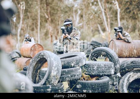 Paintball-, Kriegs- oder Schützenmänner in einem Schießspiel, die auf einem lustigen Schlachtfeld spielen oder trainieren. Missionsfokussiertes Militär- oder Armeeteam mit Waffen Stockfoto