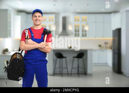 Junger Klempner mit Werkzeugtasche in der Küche, Platz für Text Stockfoto