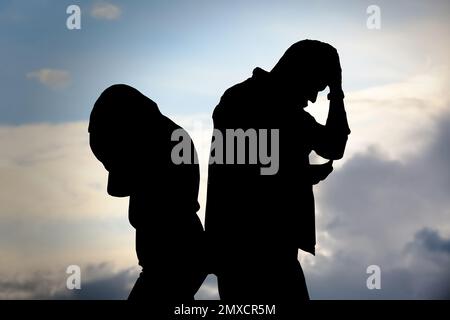 Silhouetten eines streitenden Paares gegen den bewölkten Himmel. Beziehungsprobleme Stockfoto