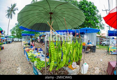 24. Januar 2023 - Chumphon Thailand - überfüllter Gemüsemarkt. Verkäufer mit einer Maske hinter dem Stand. Stockfoto