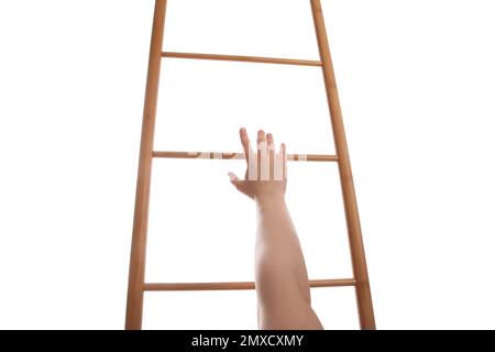 Eine Frau, die eine hölzerne Leiter hochklettert, vor weißem Hintergrund, Nahaufnahme Stockfoto